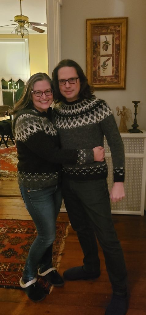 Susan and Graham wearing sweaters in their hallway at Christmas