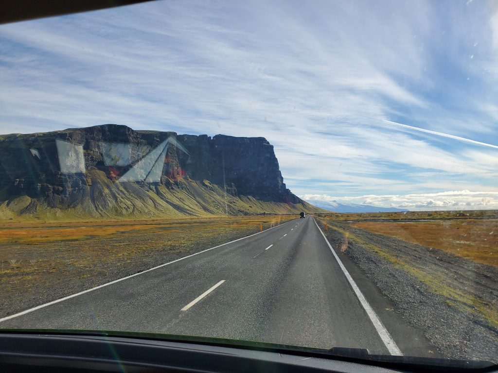 road with mountain on left and mountains in distance.