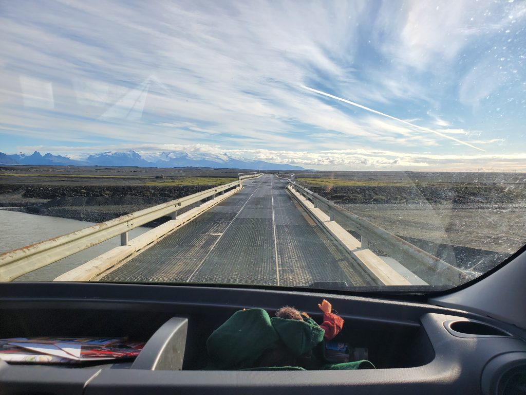 view from van windshield crossing a bridge with the glacier in the distance