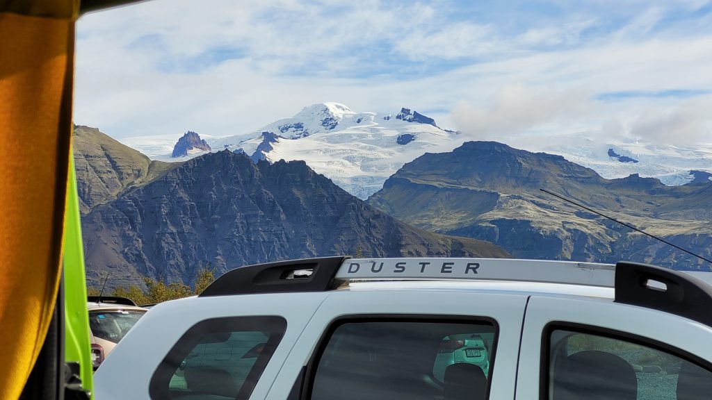 view from camper van shows an SUV with a glacier above it