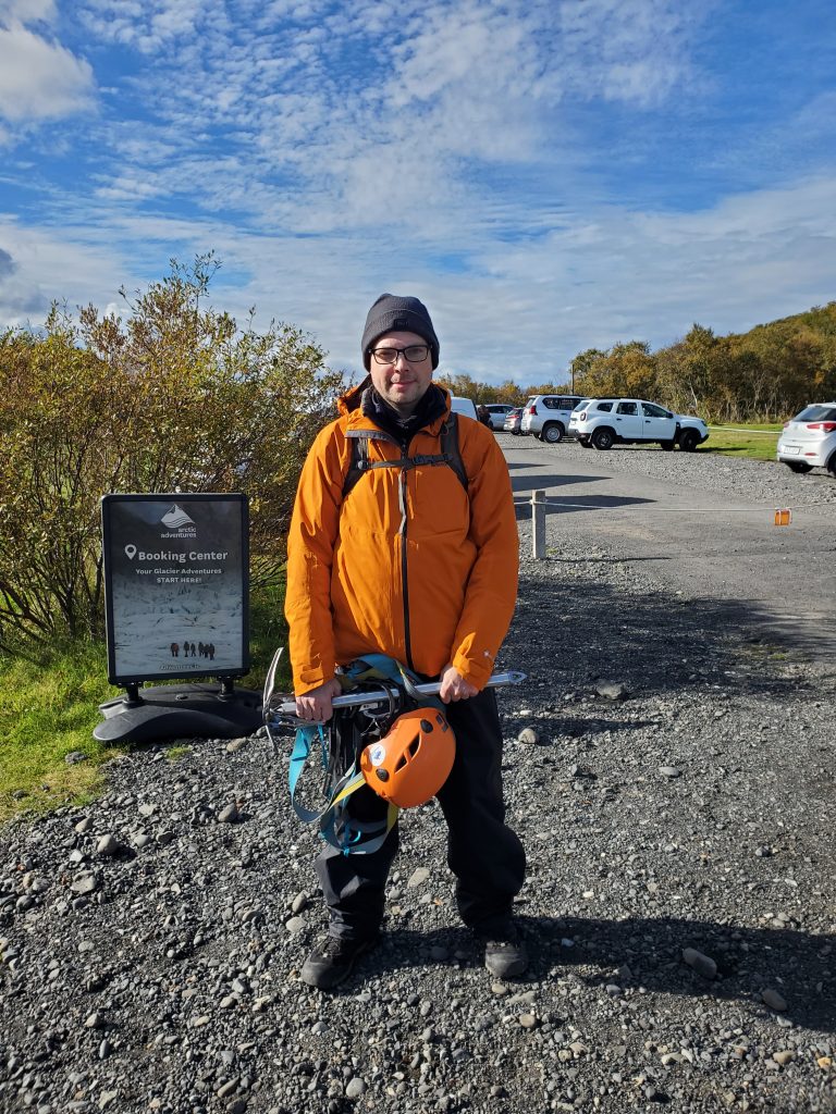 Graham standing in front of the Arctic Advenrtures sign wearing glacier hiking gear