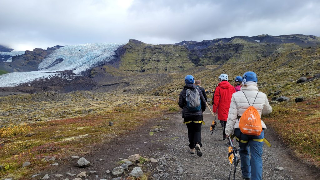 People walking toward a mountain with a glacier cap
