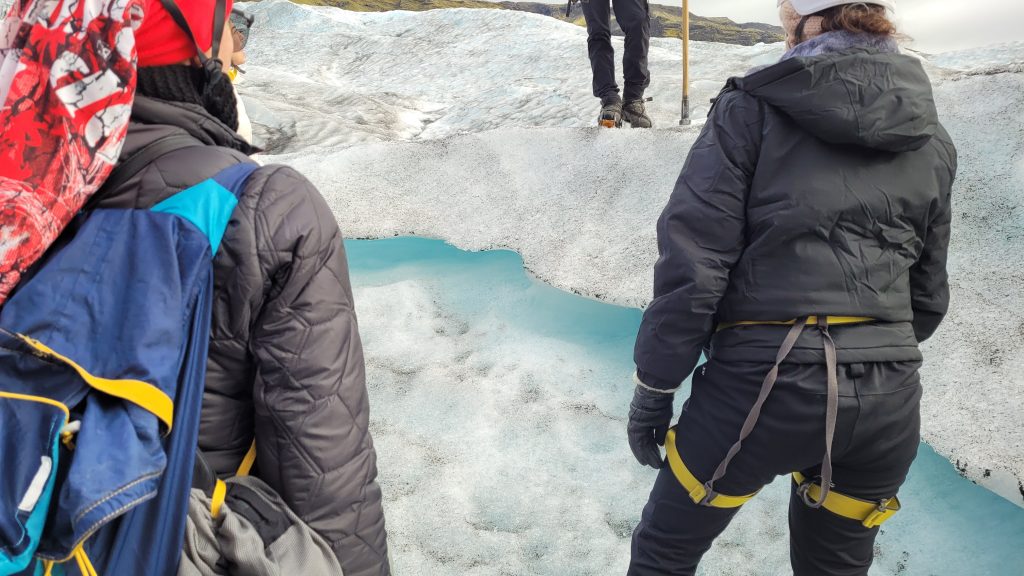 people looking at a ribbon of blue ice in the glacier