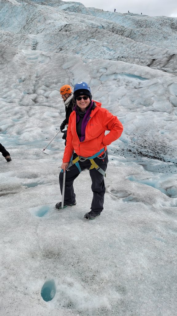 Susan on a glacier standing next to a glacier hole