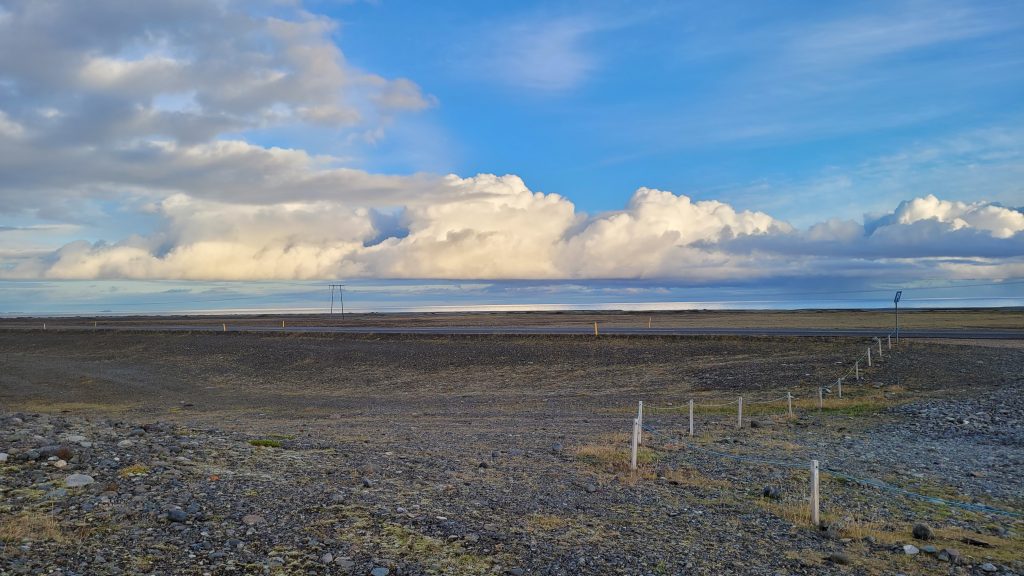 gravel and sand with a road bisecting it...ocean in the distance