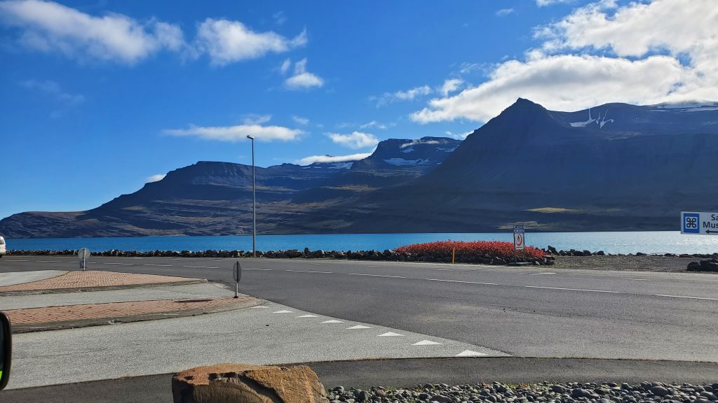 road beside ocean with mountain in the distance