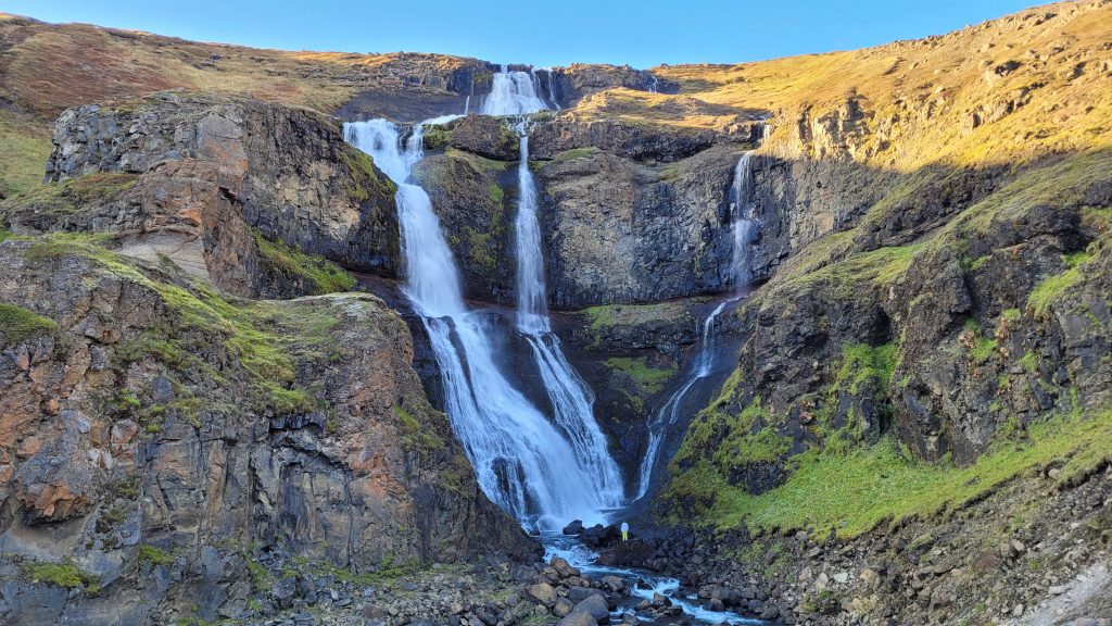 Man standing at bottom of waterfall