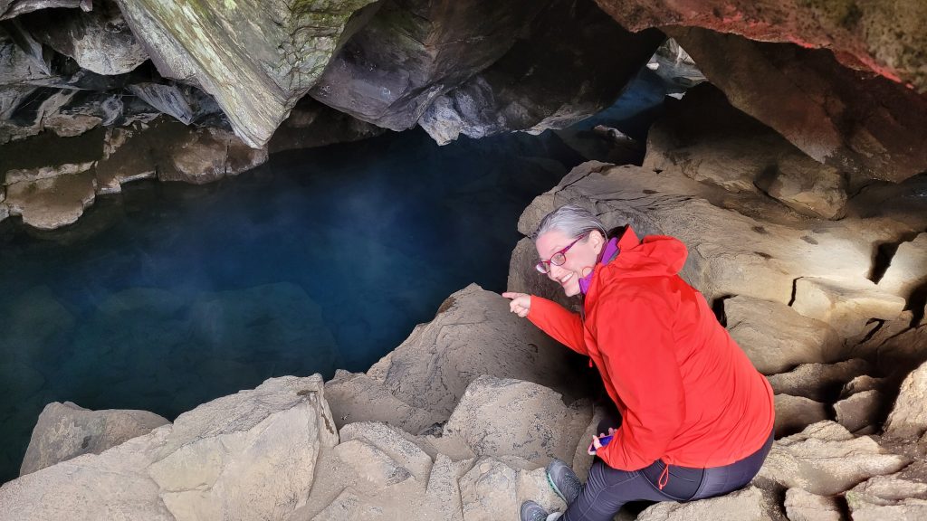 person in cave with thermal spring