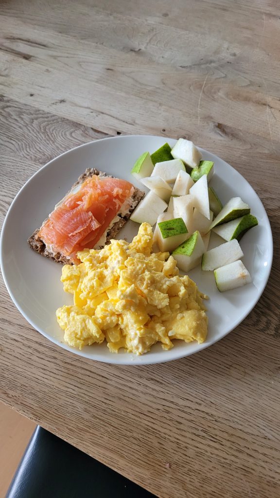 lox on rye cracker, scrambled eggs, chopped pear on a plate