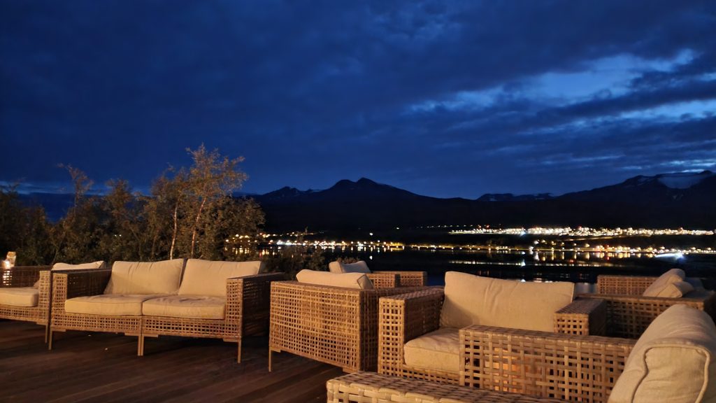 cushioned deck chairs with a city skyline at night in background