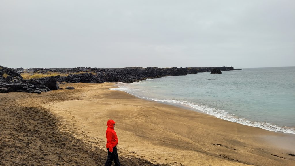 person in orange rain jacket on the beach