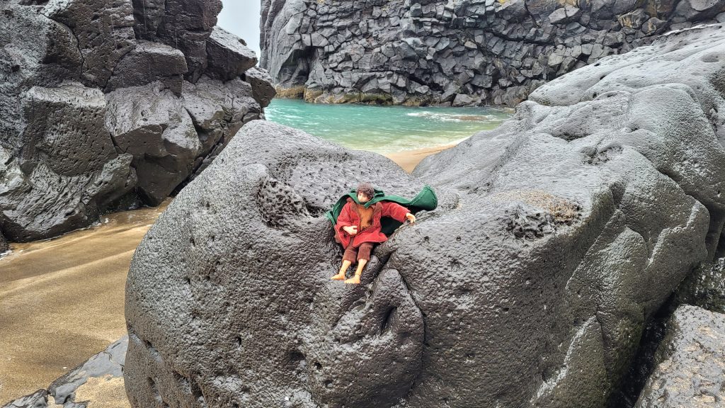 Frodo doll on rock at the beach