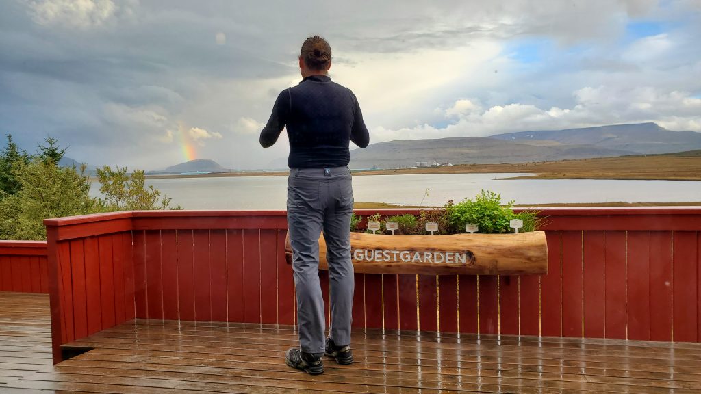 Graham on a deck taking pictures of a rainbow