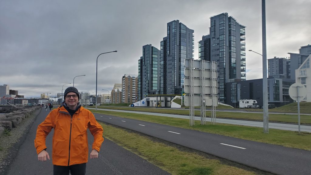 Graham walking on a sidewalk with buildings to his right